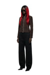 A model wearing a dark brown cropped zip-up jacket, black wide-leg trousers, and black pointed shoes, with long black hair featuring vibrant red streaks and black sunglasses, set against a plain white background.