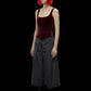 A digital render of a female model with vibrant orange hair and sunglasses, wearing a burgundy velvet corset top, dark gray wide-leg cropped pants, and black boots against a solid black background.