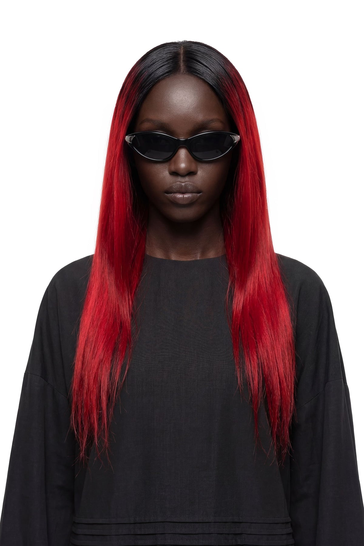 A model with long, straight black hair featuring vibrant red ombre ends, wearing black sunglasses and a black top against a solid white background.