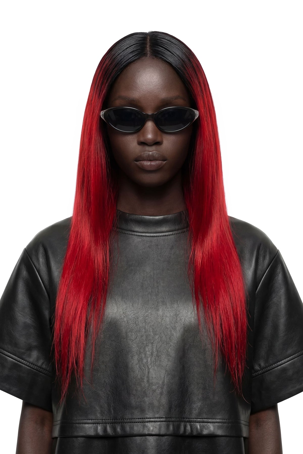 A model with long, straight black hair featuring vibrant red ombre ends, wearing black sunglasses and a black leather top against a solid white background.