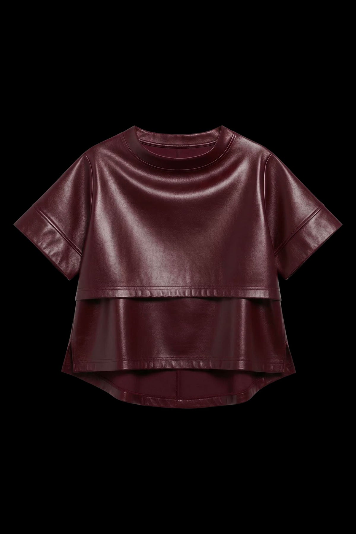 A short-sleeve cropped faux-leather top in a deep burgundy color, featuring a layered asymmetrical hem, displayed against a solid black background.