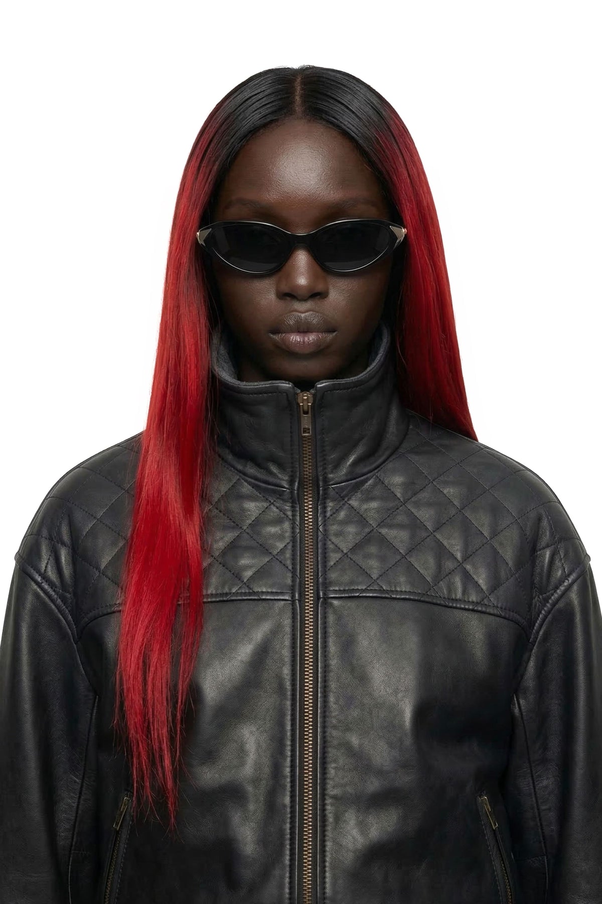 A model wearing a black quilted leather jacket and black cat-eye sunglasses, featuring long, straight black hair with vibrant red highlights, set against a plain white background.
