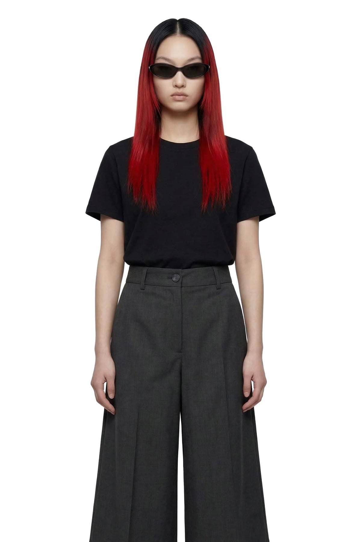 A model with long black hair and vibrant red ends, wearing a black short-sleeve t-shirt and dark gray wide-leg trousers, styled with black sunglasses against a plain white background.
