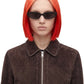 A model with a vibrant red-to-blonde ombre bob haircut wearing black sunglasses and a dark brown textured zip-up jacket, shot against a solid white background.
