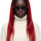 A model with long, straight black hair featuring vibrant red ombre ends, wearing a cream-colored ribbed turtleneck sweater and black sunglasses, set against a plain white background.