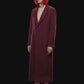 A long burgundy wool-blend coat with notch lapels, front closure, and side pockets, shown against a solid black background.
