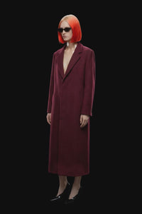 A long burgundy wool-blend coat with notch lapels, front closure, and side pockets, shown against a solid black background.