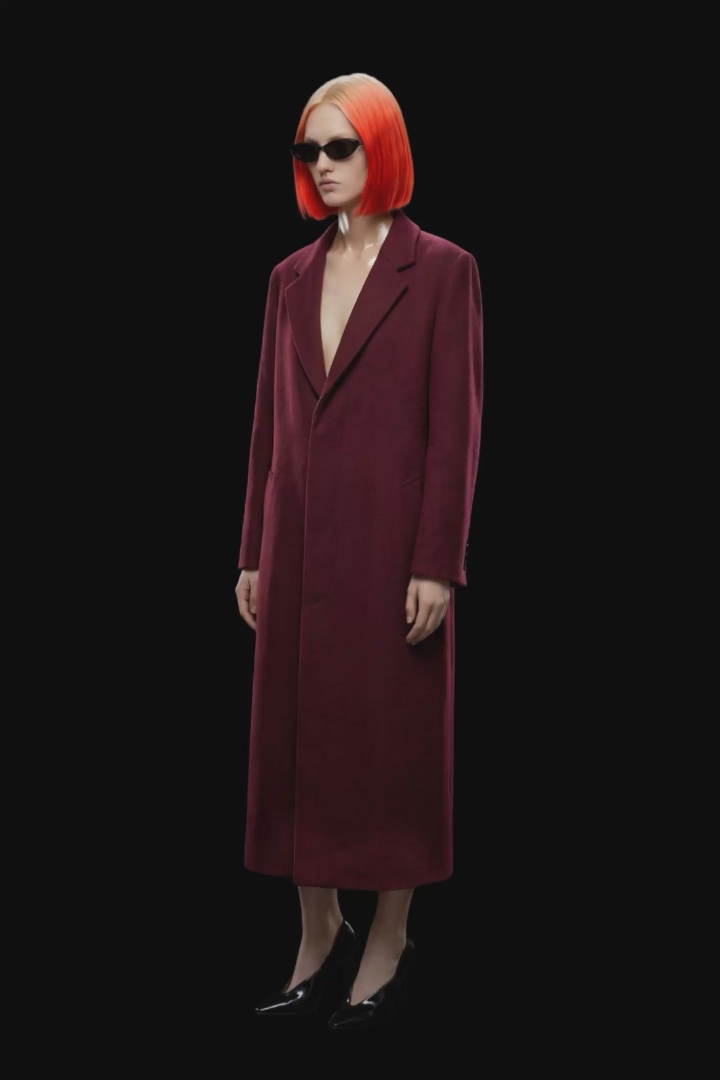 A long burgundy wool-blend coat with notch lapels, front closure, and side pockets, shown against a solid black background.