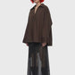 A black midi skirt with a structured waistband and an asymmetrical draped overlay, shown against a plain white background.