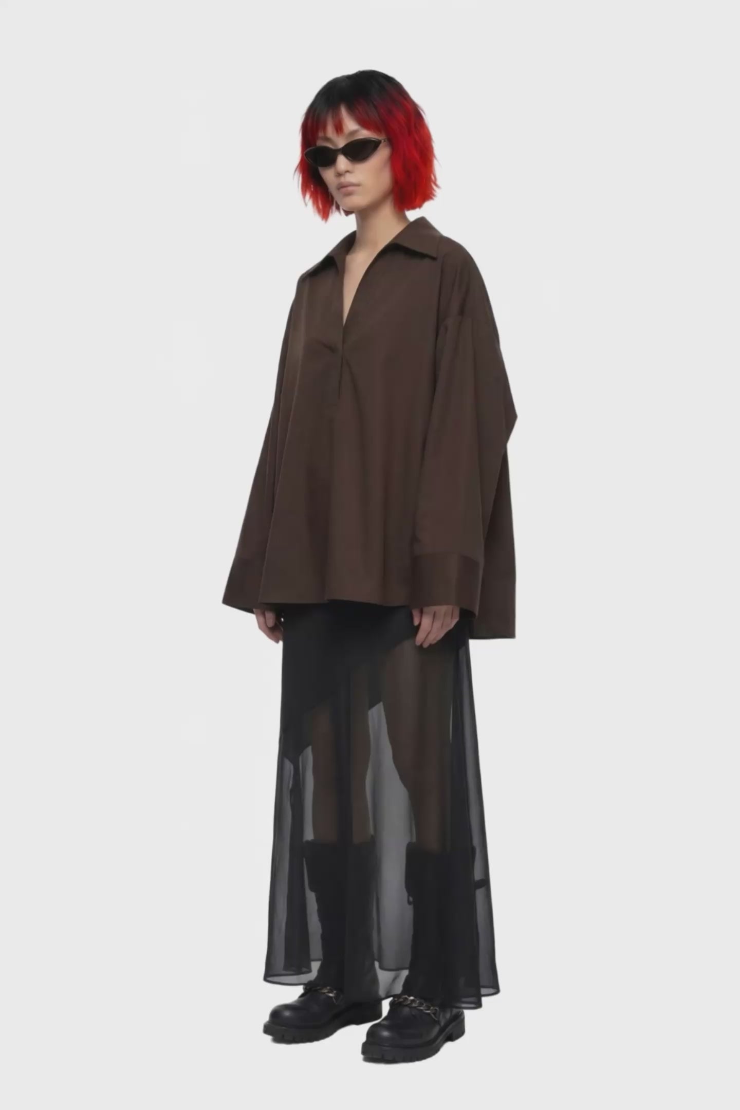 A black midi skirt with a structured waistband and an asymmetrical draped overlay, shown against a plain white background.