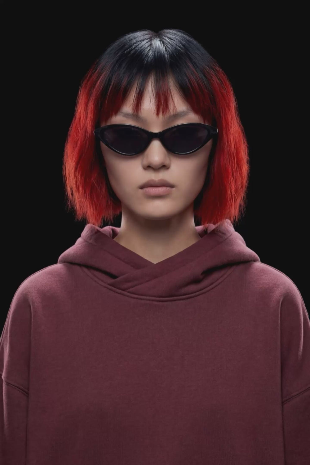 A dark burgundy pullover hoodie with a front kangaroo pocket and subtle tonal side details, displayed against a solid black background.