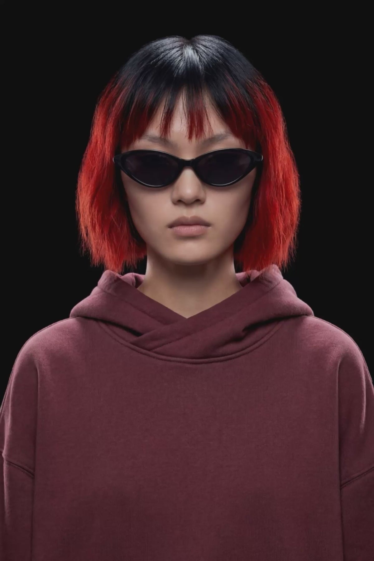 A dark burgundy pullover hoodie with a front kangaroo pocket and subtle tonal side details, displayed against a solid black background.