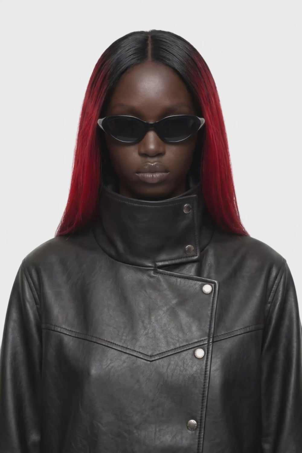 A black leather jacket with a high mock neck, asymmetrical snap button closure, and ribbed sleeve detailing, shown against a plain white background.