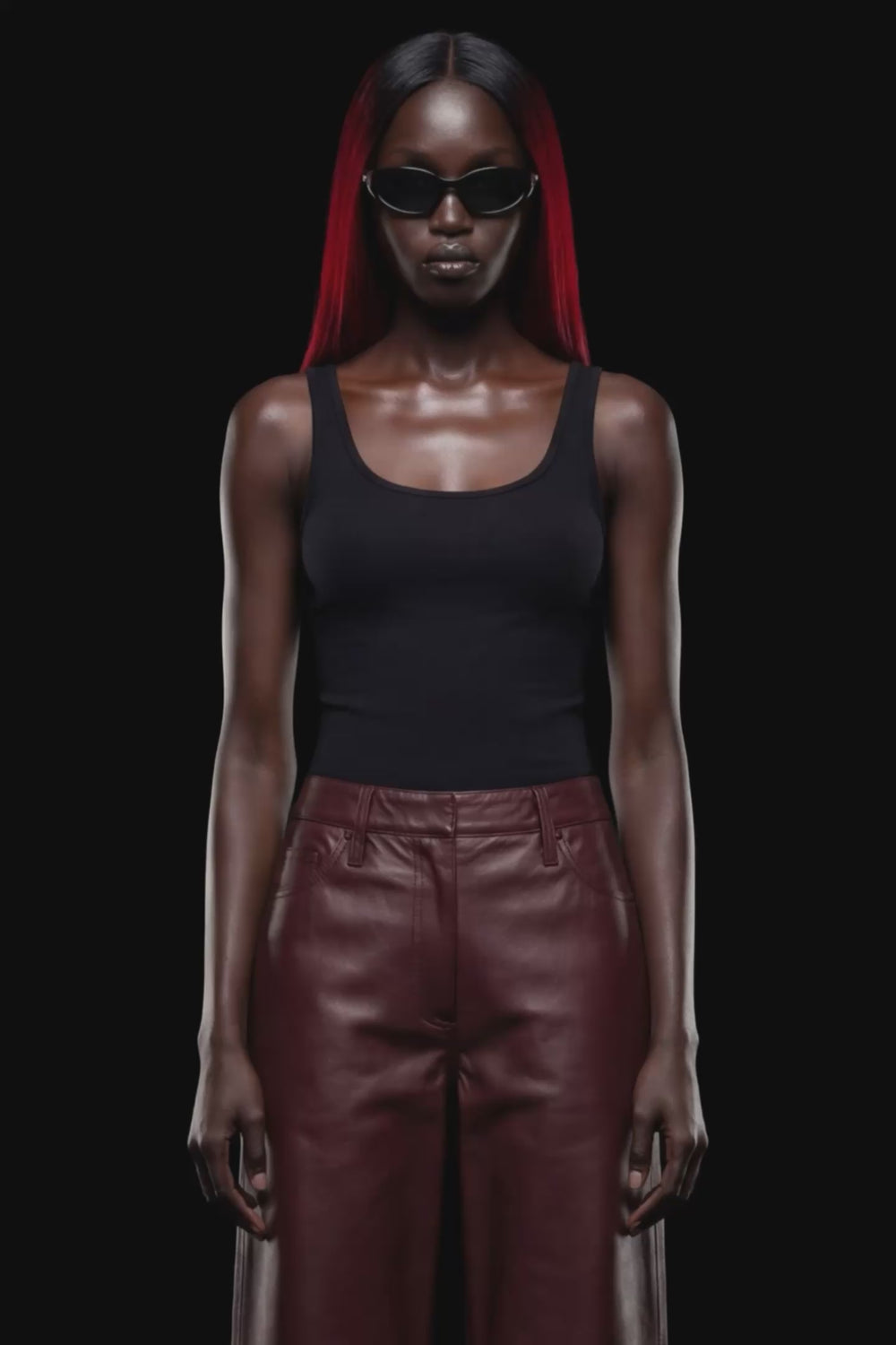 A pair of dark reddish-brown faux leather cropped pants with a wide leg, shown against a solid black 