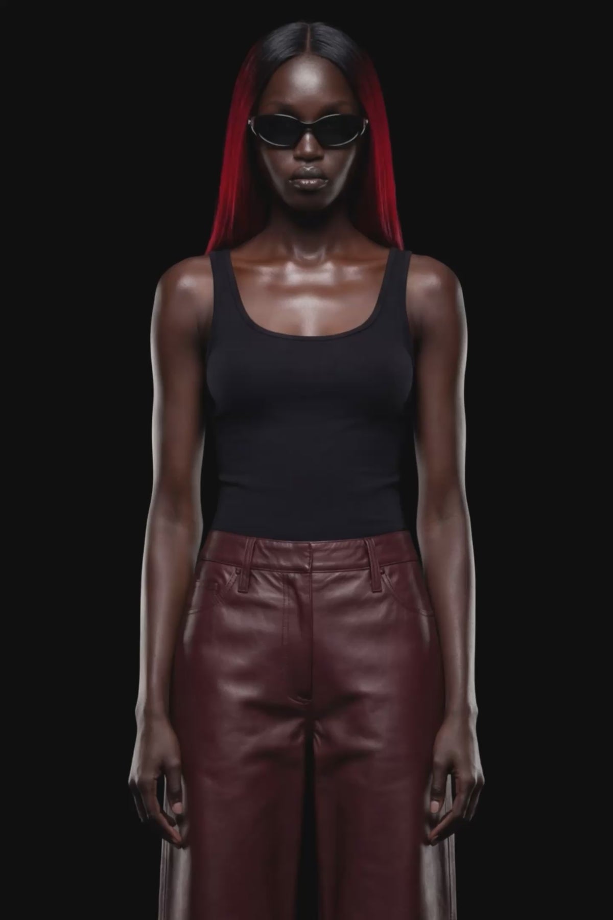 A pair of dark reddish-brown faux leather cropped pants with a wide leg, shown against a solid black 
