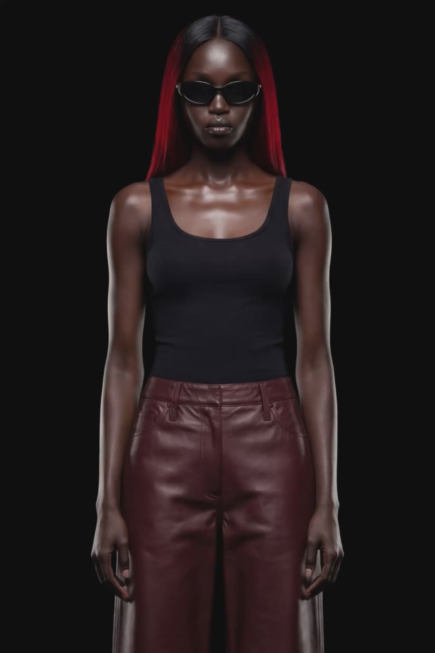 A pair of dark reddish-brown faux leather cropped pants with a wide leg, shown against a solid black 