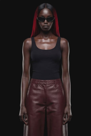 A pair of dark reddish-brown faux leather cropped pants with a wide leg, shown against a solid black 
